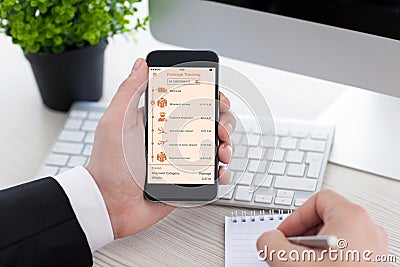 Man holding phone with app tracking delivery package on screen Stock Photo