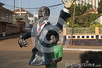 Man holding a plastic figurine of a polititian during the Carnival celebrations in the city of Bisssau. Editorial Stock Photo