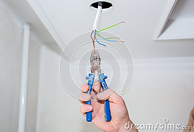 Man is holding pliers in his hands. Electrical insulator for light bulb. Adhesive tape for maintenance repair works in the flat. Stock Photo