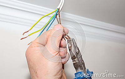 Man is holding pliers in his hands. Electrical insulator for light bulb. Adhesive tape for maintenance repair works in the flat. Stock Photo