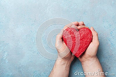 Man holding a red heart in hands top view. Healthy, love, donation organ, donor, hope and cardiology concept. Stock Photo