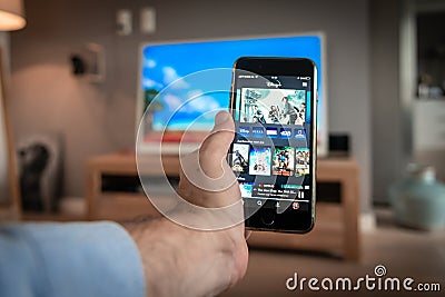 Man holding smartphone, movie is on TV, Disney+ online video, content streaming subscription service. Disney Plus home screen on t Editorial Stock Photo