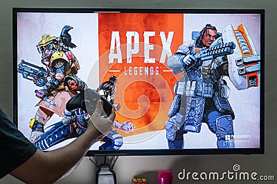 Man holding steam controller in front of a screen loading apex legends a massively online multiplayer shooter game with Editorial Stock Photo