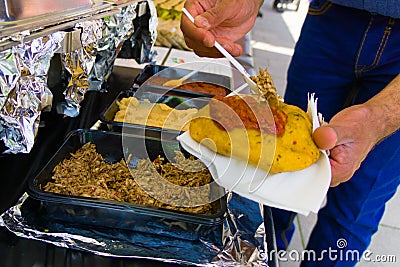 Man holding a suriname bara next to the topping bar Stock Photo