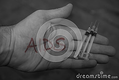 Man holding syringes needles with the word aids written on his hands Stock Photo