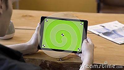 Man holding a tablet in his hands without motions, green screen with tracking marks. Stock footage. Male looking at his Stock Photo