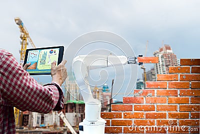 Man holding a tablet Remote control Smart robot industry 4. 0 arm brick building construction human force Stock Photo