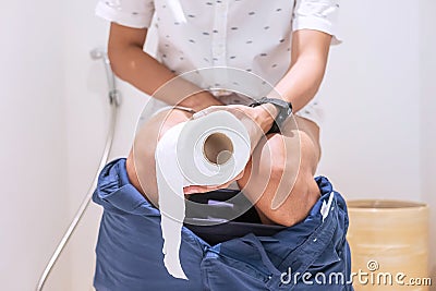 Man holding toilet paper roll during sit on toilet bowl diarrhea, constipated period, infection, Healthcare, Insurance, Medical Stock Photo