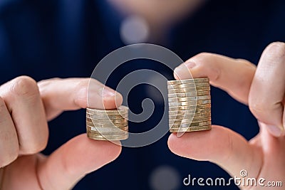 Man Holding Two Coin Stacks Stock Photo