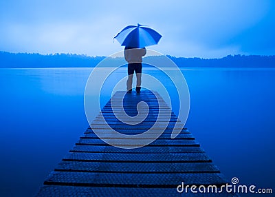 Man Holding Umbrella on a Jetty Tranquil Lake Concept Stock Photo