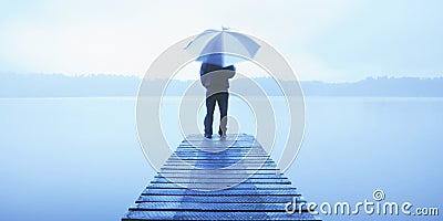 Man Holding an Umbrella on a Jetty by Tranquil Lake Concept Stock Photo