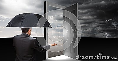 Man holding umbrella and open door with surreal grey cloudy sky Stock Photo