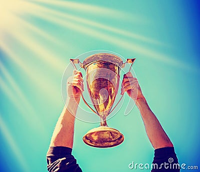 A man holding up a gold trophy cup as a winner in a competition Stock Photo