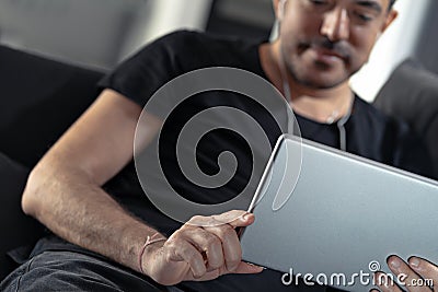 Man holding using digital tablet and headphones sitting on a sofa. Online education, working, video call Stock Photo