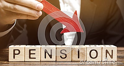 A man holds an arrow down over wooden blocks with the word Pension. Fall / reduction pension payments. Retirement. Financing Stock Photo