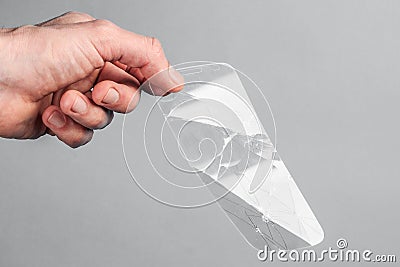Man holds broken, broken smartphone safety glass in his hand on grey background. concept of fragile equipment Stock Photo