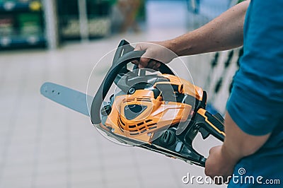 A man holds a chain saw in his hand. A buyer in a hardware store selects a product Stock Photo