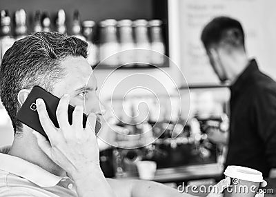 Man holds cup of drink while have mobile conversation. Coffee to go useful option for busy people. Call friend to have Stock Photo