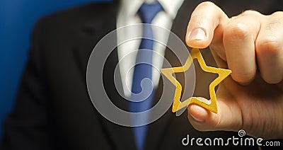 Man holds a golden star in his hand. Symbol of success and excellence. Good reputation, prestige, high recognition. Status, rating Stock Photo