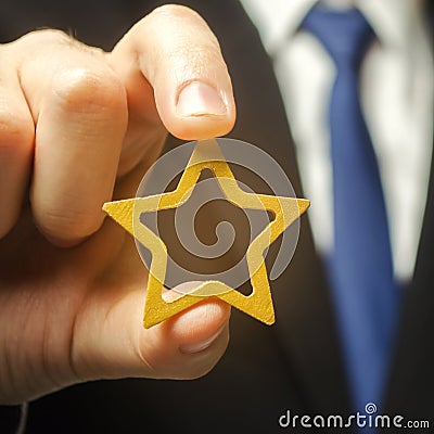 Man holds a golden star in his hand. Symbol of success and excellence. Good reputation, prestige, high recognition. Status, rating Stock Photo