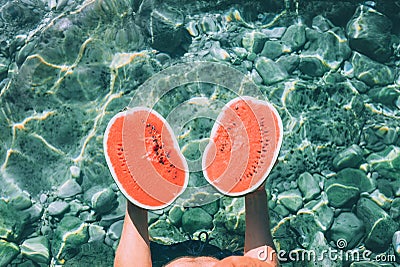 Man holds in hands two melon halfs and stands in crystal clear s Stock Photo
