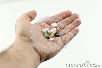 The man holds in his hand pills, vitamins, medicines on a white background. Outstretched hand with handful of pills Stock Photo
