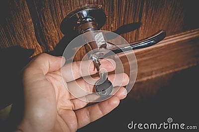 A man holds in his hand a small light broken key against the background of a door lock Stock Photo