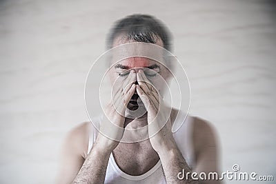 The man holds his nose and sinus area with fingers in obvious pain from a head ache in the front forehead area Stock Photo