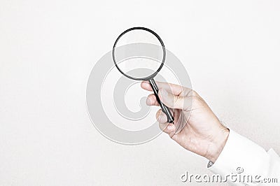 Man holds magnifying glass on wall background. Concept of search, recruitment and job search Stock Photo