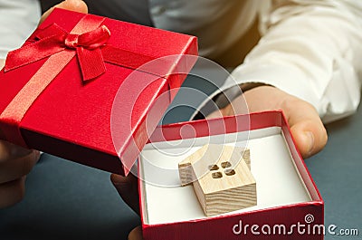 Man holds a miniature house in a gift box. Housing as a gift. Win an apartment in the lottery. To inherit property. Holiday Stock Photo