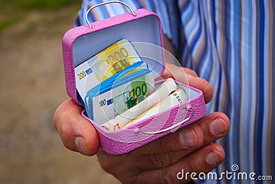 A Man Holds A Miniature Pink Suitcase With Chocolate And Real Euro Notes The Common Currency Of The European Union Stock Photo