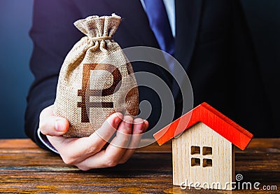 Man holds out a russian ruble bag near the house. Bank approval for issuing a mortgage loan. Property appraisal. Favorable terms Stock Photo