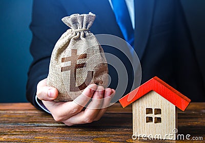 Man holds out a turkish lira bag near the house. Bank approval for issuing a mortgage loan. Home purchase, invest in real estate. Stock Photo