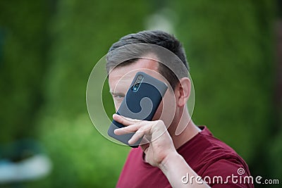 A man holds a phone in a protective case. phone safety from falling. bumper on the phone. dark phone. place to write. Smartphone Stock Photo