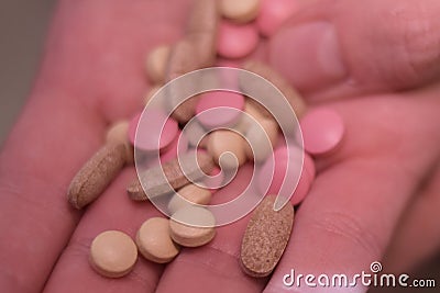 A man holds pills in his hands. Male hands hold many pills. Hands hold pink, white pills, medicine. Stock Photo