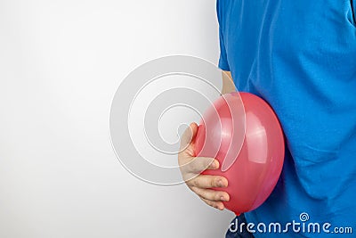 Bloating and flatulence concept. The man holds a red balloon near the abdomen, which symbolizes gas problems. Intestinal tract and Stock Photo