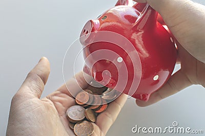 The man holds a red piggy bank and shakes out euro coins into his palm. The concept of finding money, crisis, poverty Stock Photo