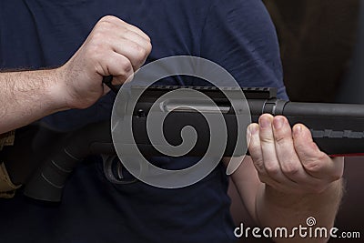 A man holds a rifle on his knees, pulls back the bolt, reloads the weapon. Concept: storage and use of firearms. Stock Photo