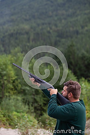 A man holds a shotgun downrange ready to fire at a clay pigeon to practice his aim in Squamish Editorial Stock Photo