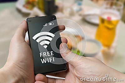 Man holds smartphone and is using free wifi in restaurant Stock Photo