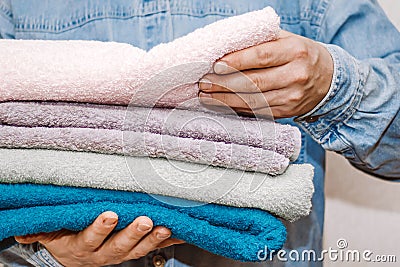 Man holds a stack of fresh terry towels. Organization and cleaning of the house. Storage and housekeeping concept Stock Photo