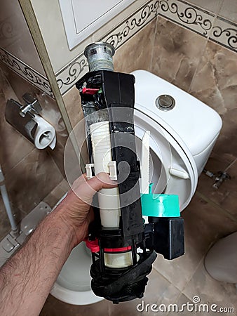 A man holds a toilet flush mechanism after repair Stock Photo