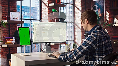 Man in home office fixing errors in application using chroma key device and PC Stock Photo