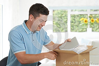 Man At Home Unwrapping Digital Tablet Bought Online Stock Photo