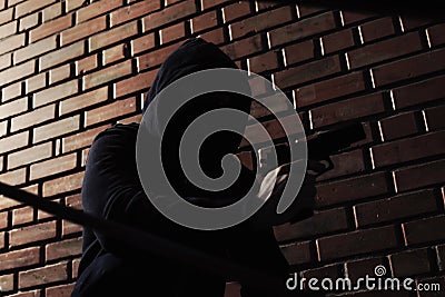 Man in hoodie with gun. Dangerous criminal Stock Photo