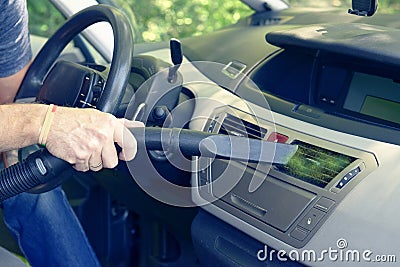 Man hoovering air vent in car Stock Photo