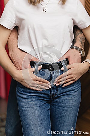 a man hugs a woman in a white shirt around the waist. Hands Stock Photo