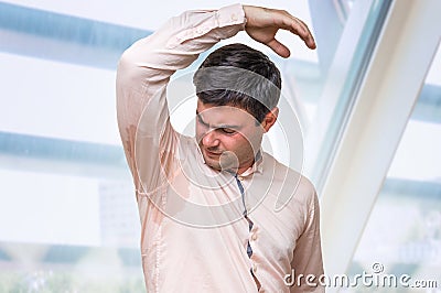 Man with hyperhidrosis sweating under armpit in office Stock Photo