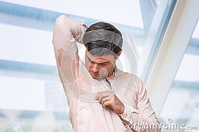 Man with hyperhidrosis sweating under armpit in office Stock Photo