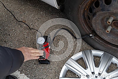 Man inflates tire with air and checking air pressure with gauge pressure in service station. Flat tire concept Stock Photo